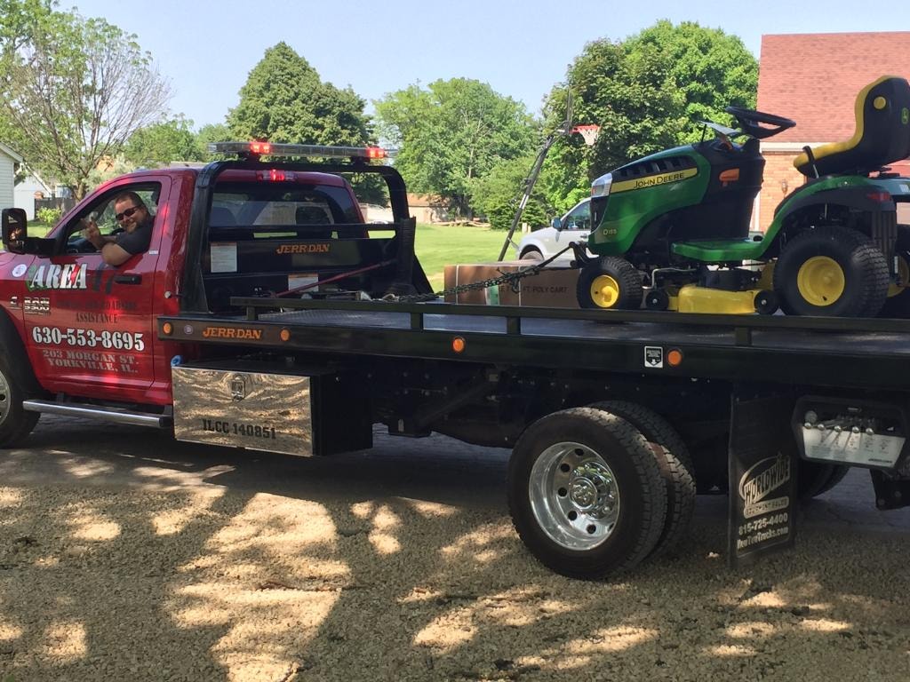 Area 47 red tow truck hauling lawn mower